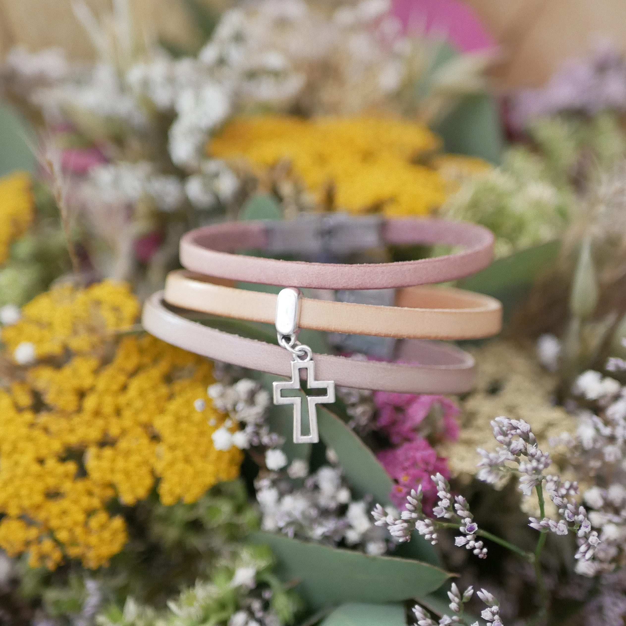 Bracelet cuir personnalisé avec pendentif croix argenté sur fleurs.