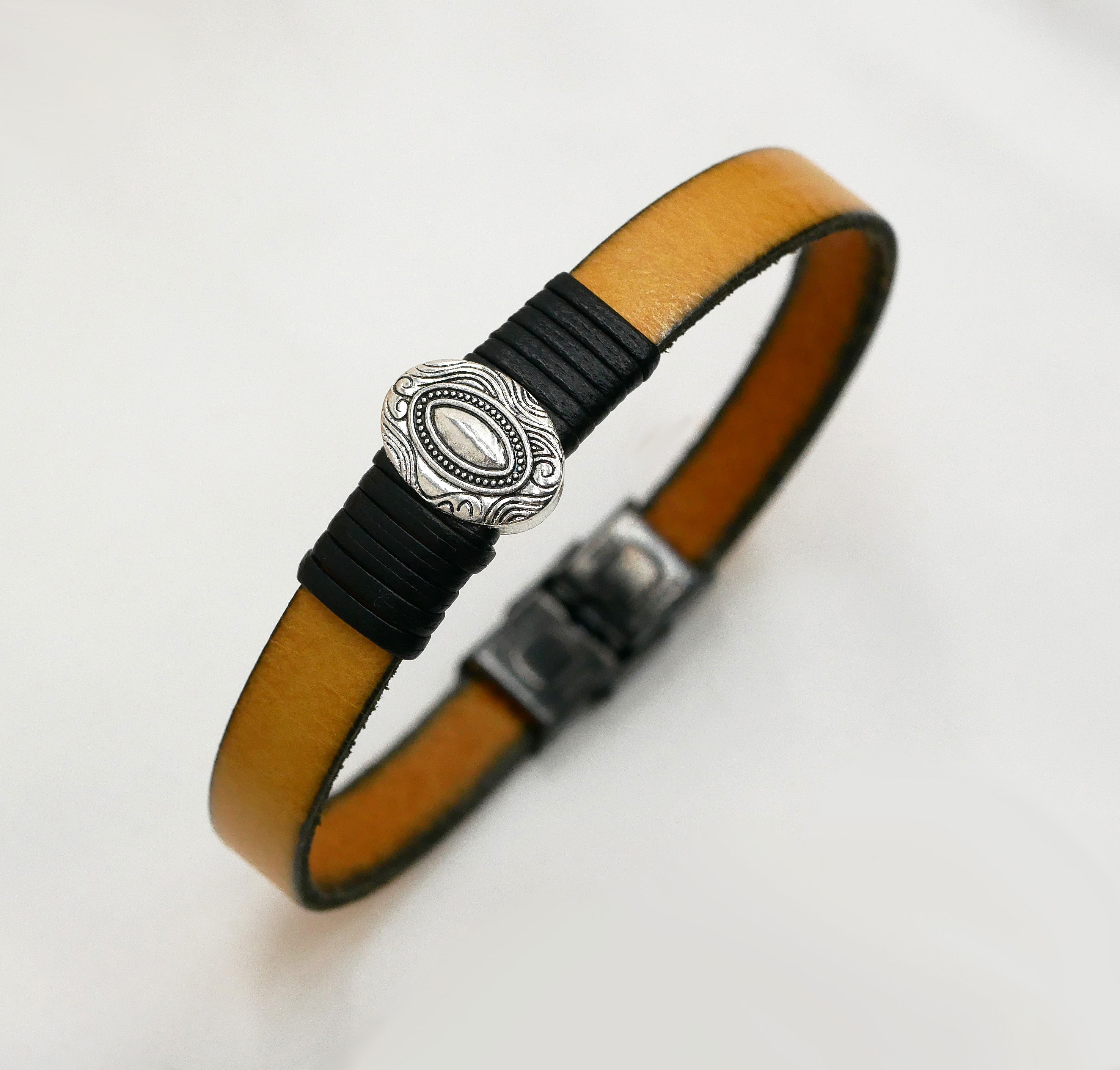 Anpassningsbar l&auml;derrem med centralt ovalt ornament inramat av fina l&auml;derdetaljer 