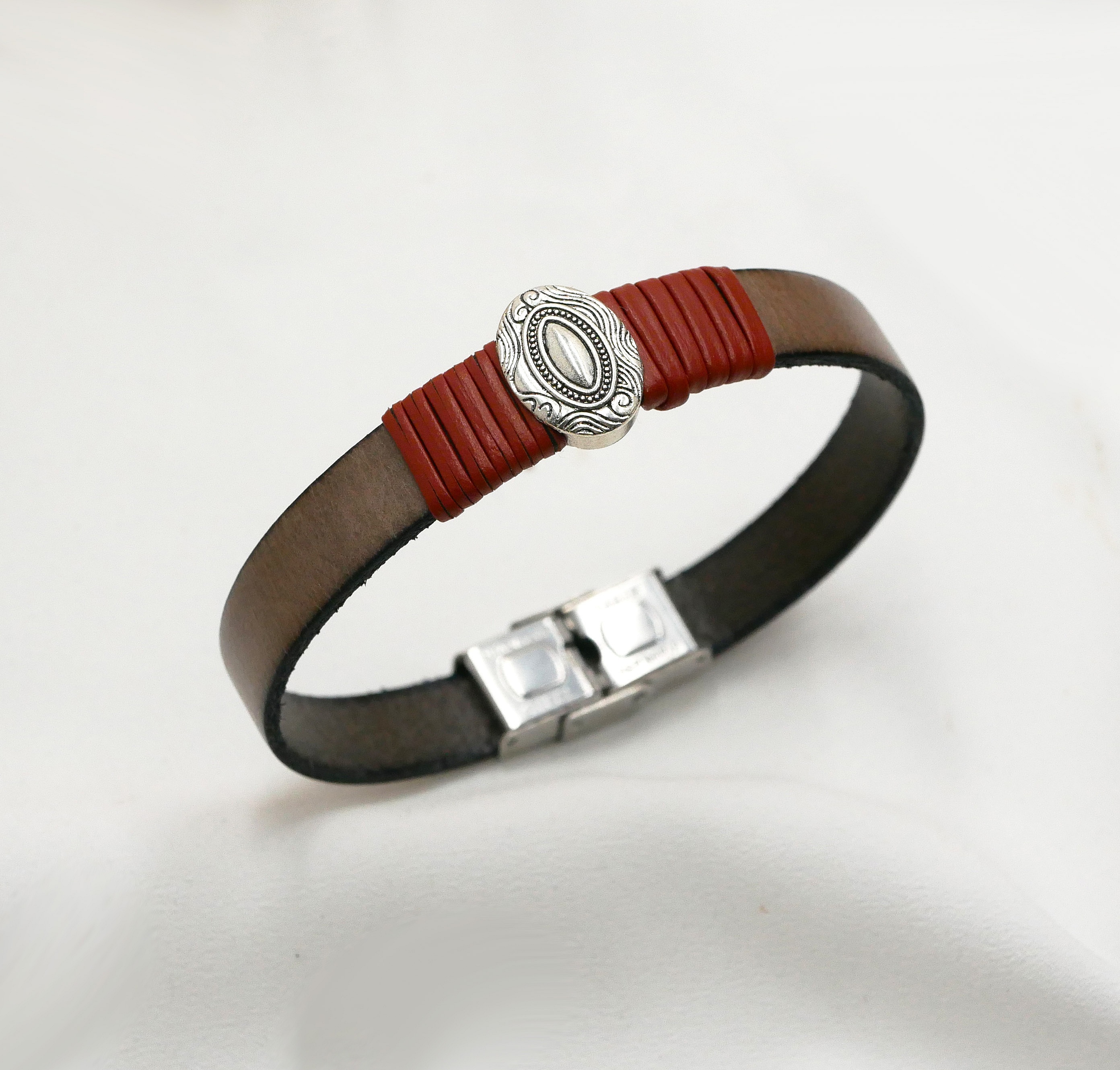 Anpassningsbar l&auml;derrem med centralt ovalt ornament inramat av fina l&auml;derdetaljer 