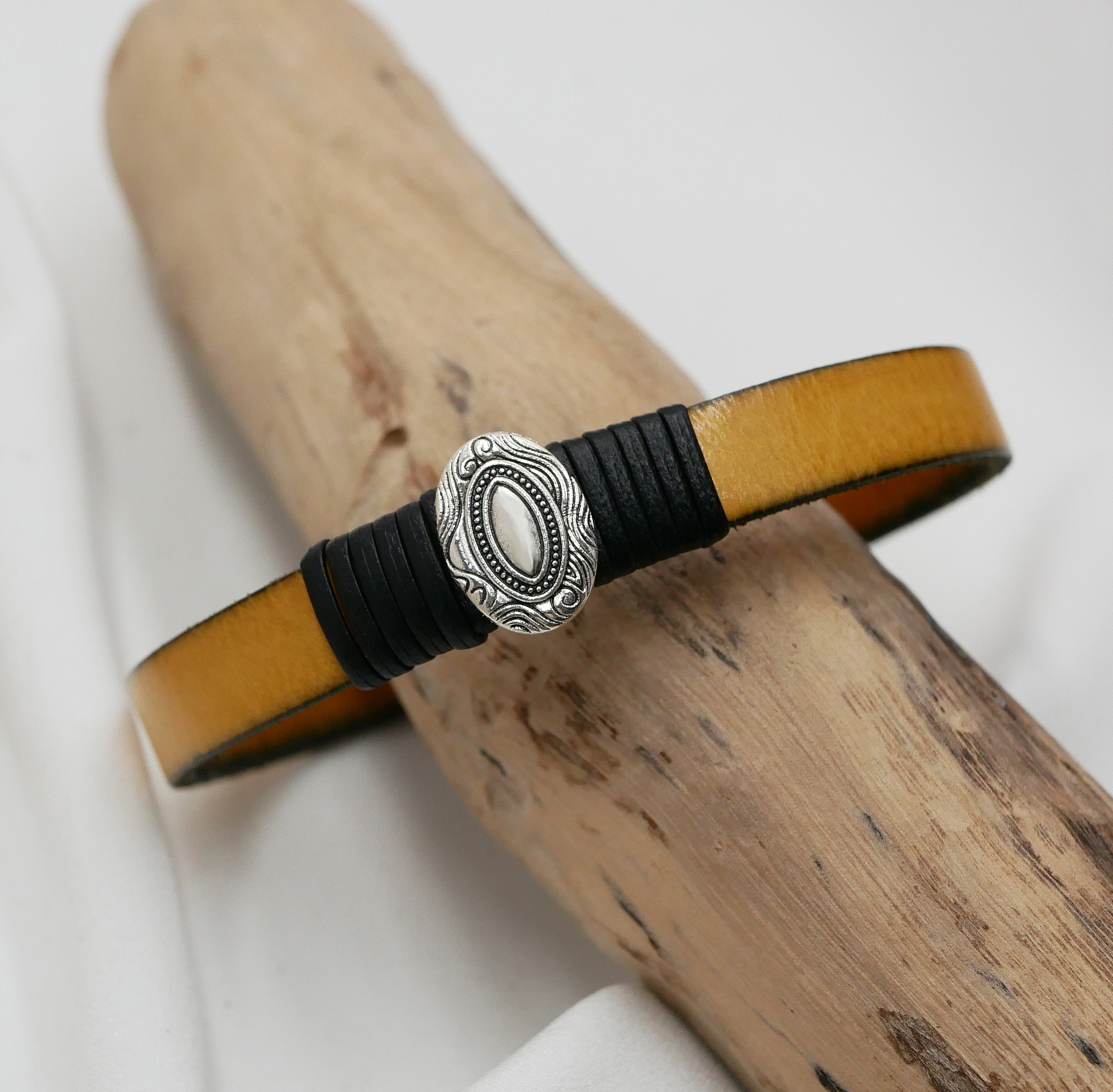 Anpassningsbar l&auml;derrem med centralt ovalt ornament inramat av fina l&auml;derdetaljer 