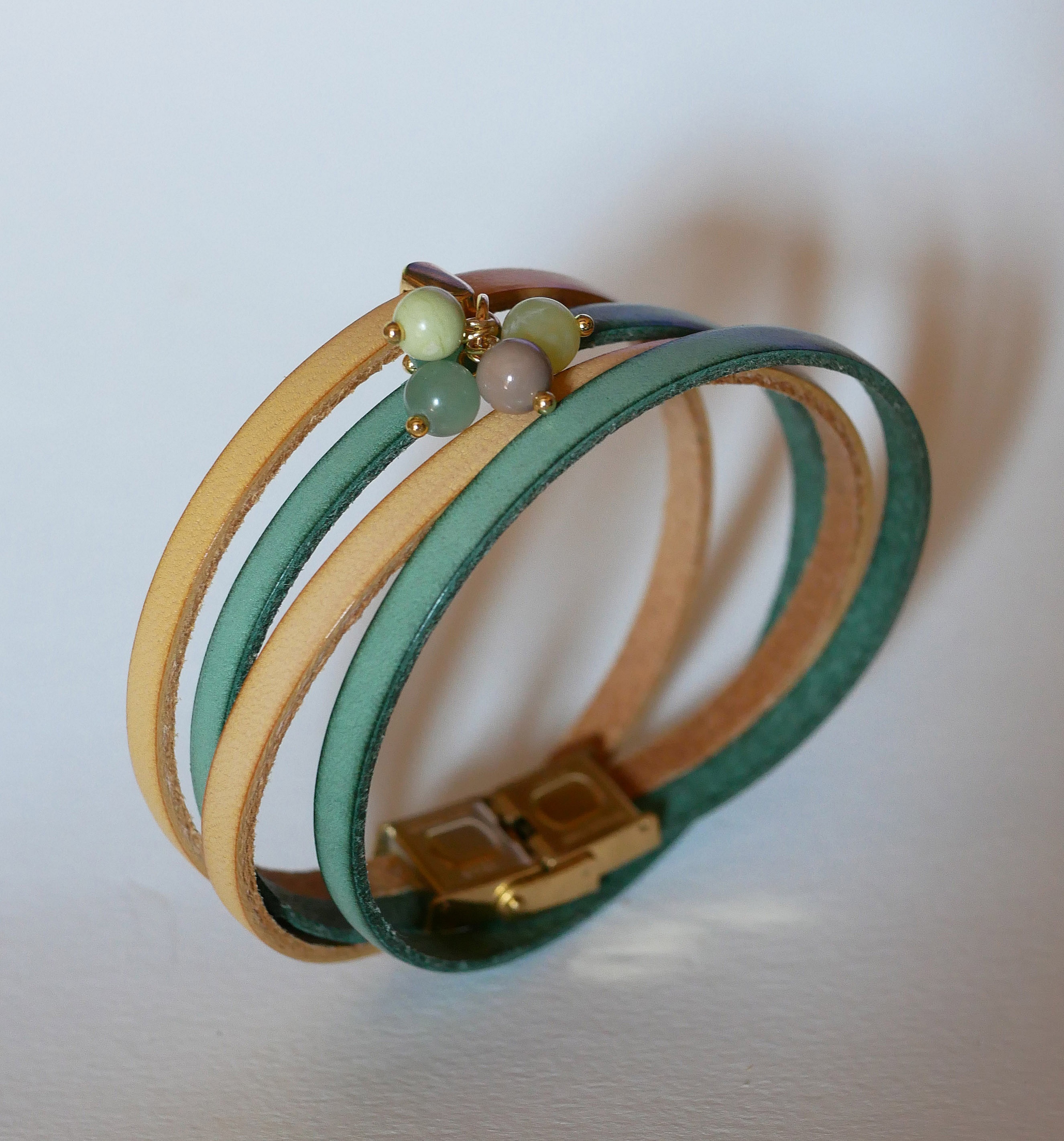 Dubbelt l&auml;derarmband dekorerat med mjuka gr&ouml;na p&auml;rlor och guldsp&auml;nne