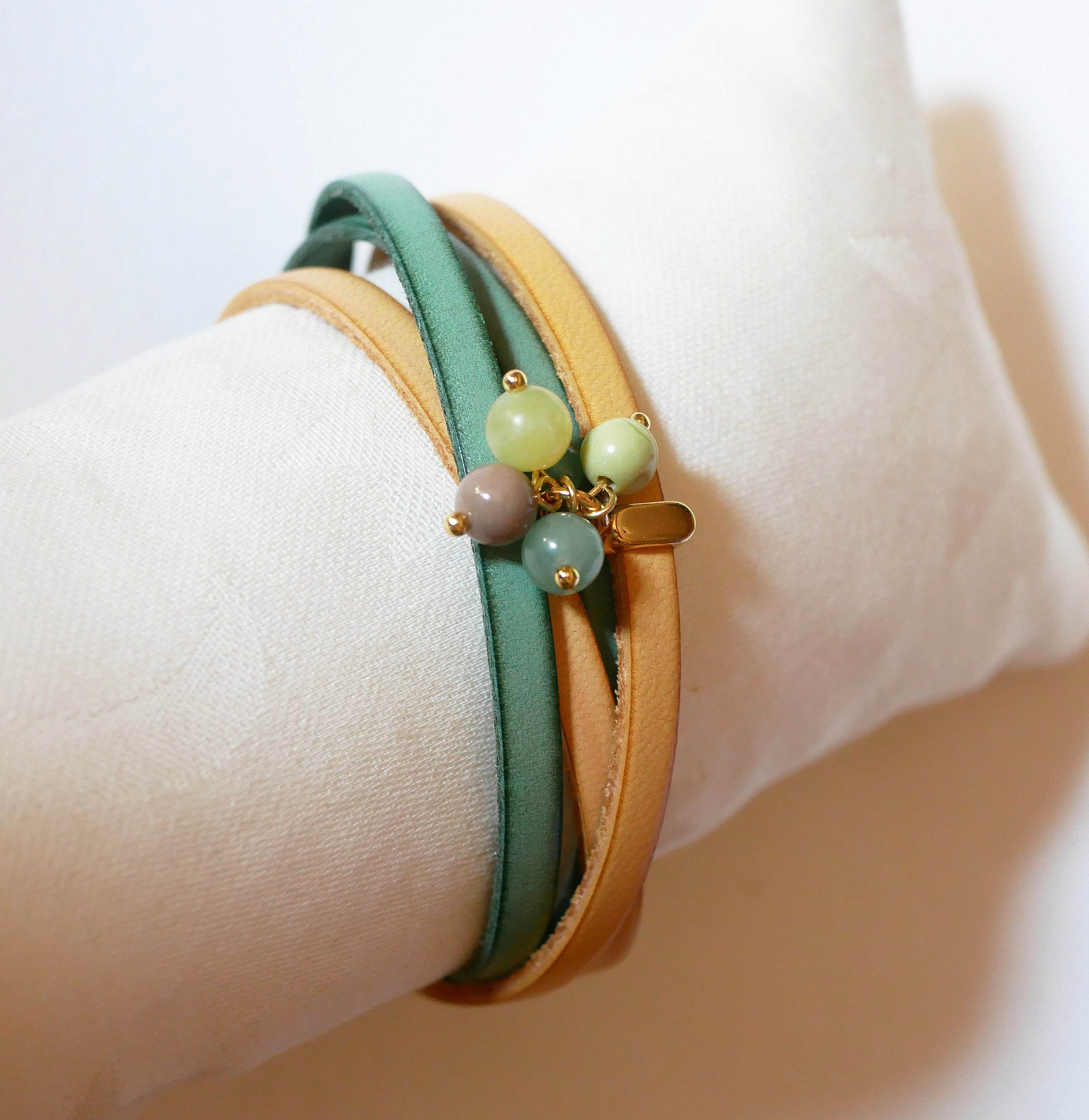 Dubbelt l&auml;derarmband dekorerat med mjuka gr&ouml;na p&auml;rlor och guldsp&auml;nne