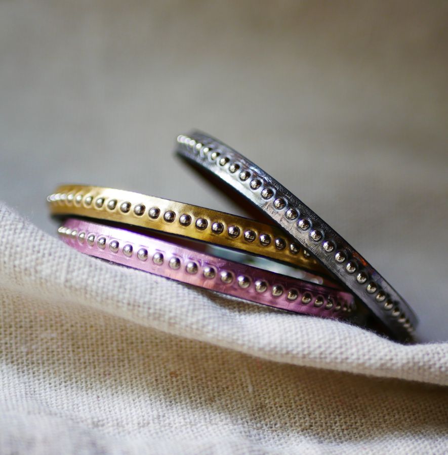 Kvinnoarmband i mörkgrått metalliskt läder med silverfärgade pärlor 