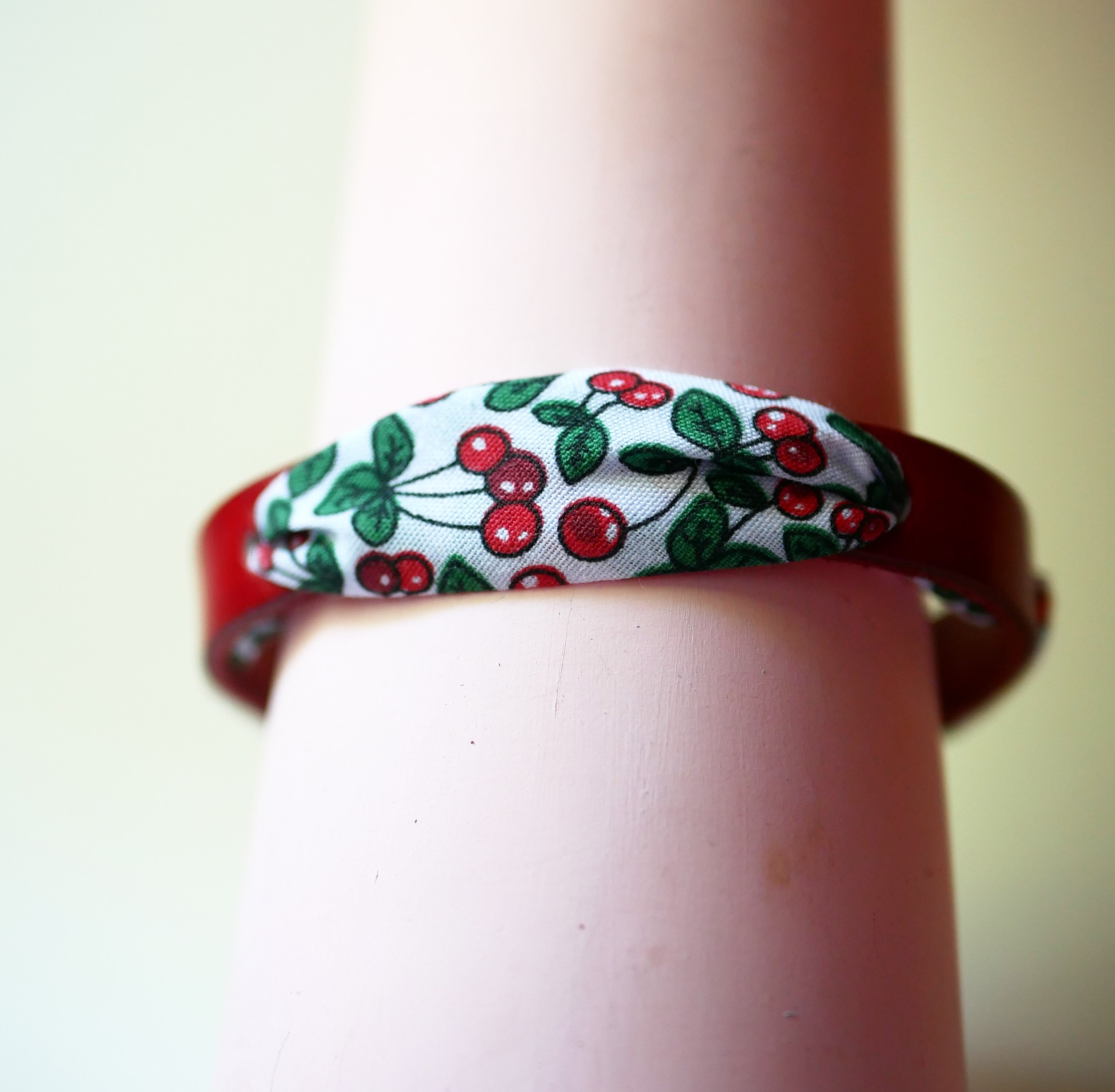 Florâme-armband med band av körsbärsfrukt på rött läder