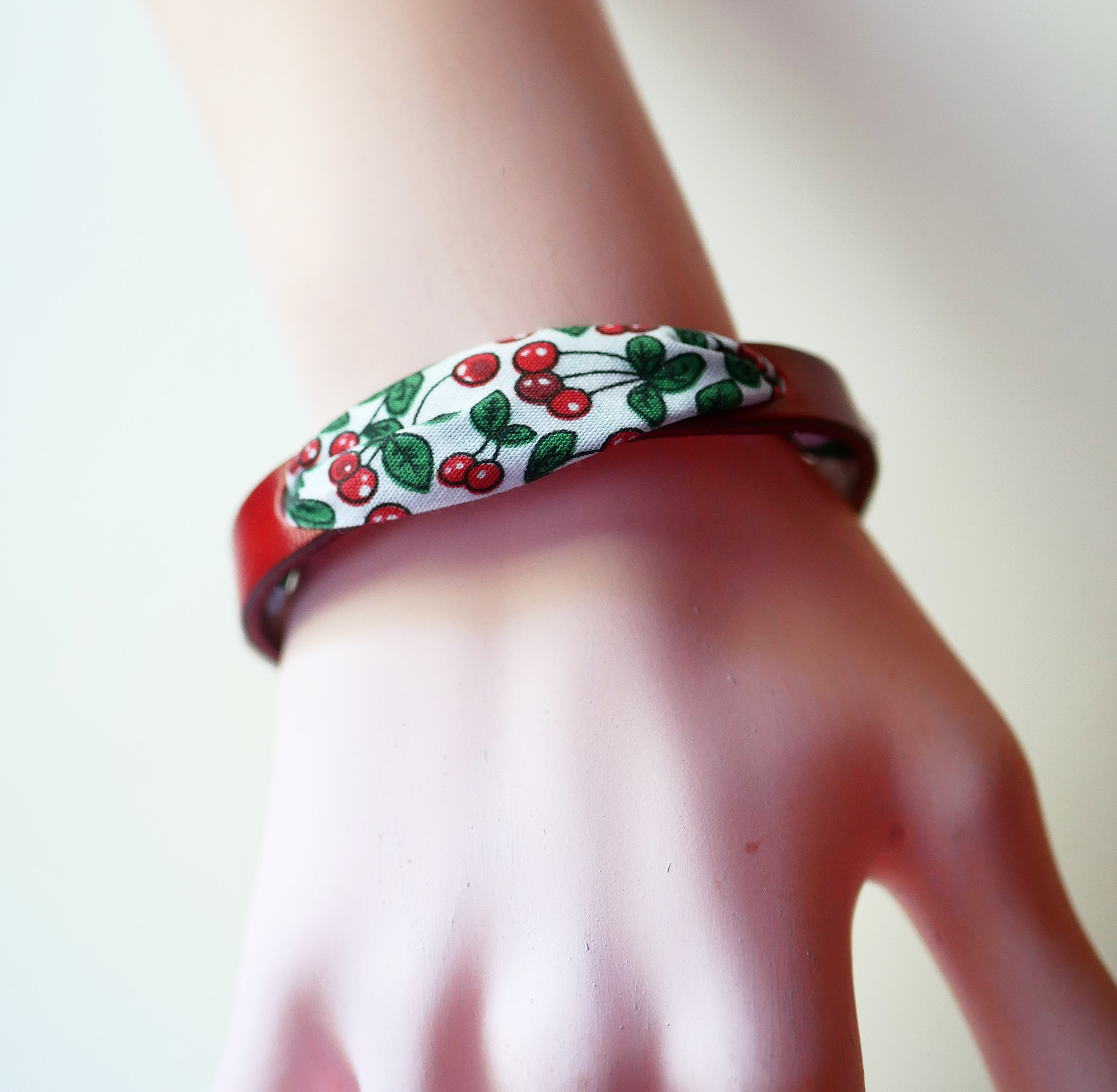 Florâme-armband med band av körsbärsfrukt på rött läder