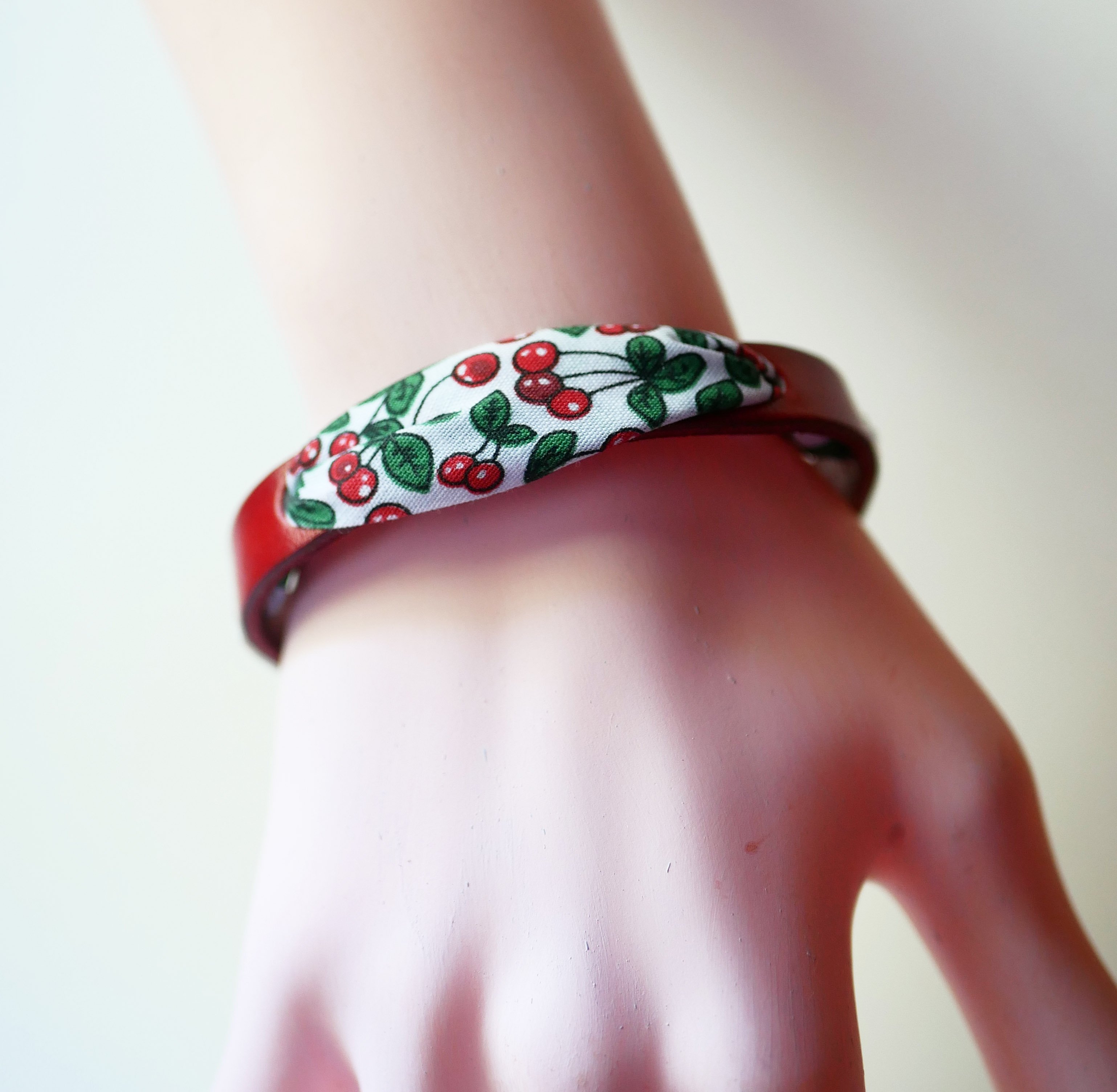 Florâme-armband med band av körsbärsfrukt på rött läder