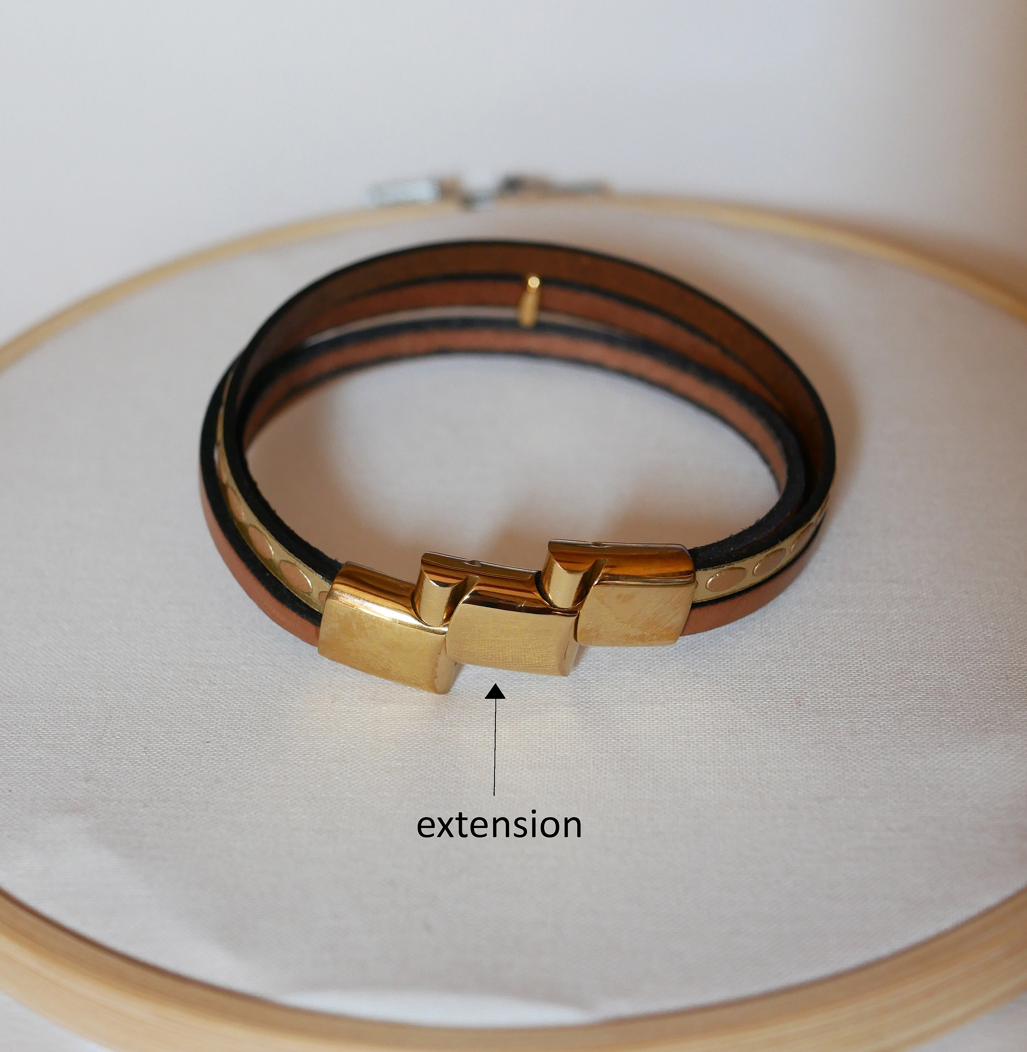 Manschettarmband i l&auml;der med flera l&auml;nkar och solstr&aring;le&ouml;gla i guld