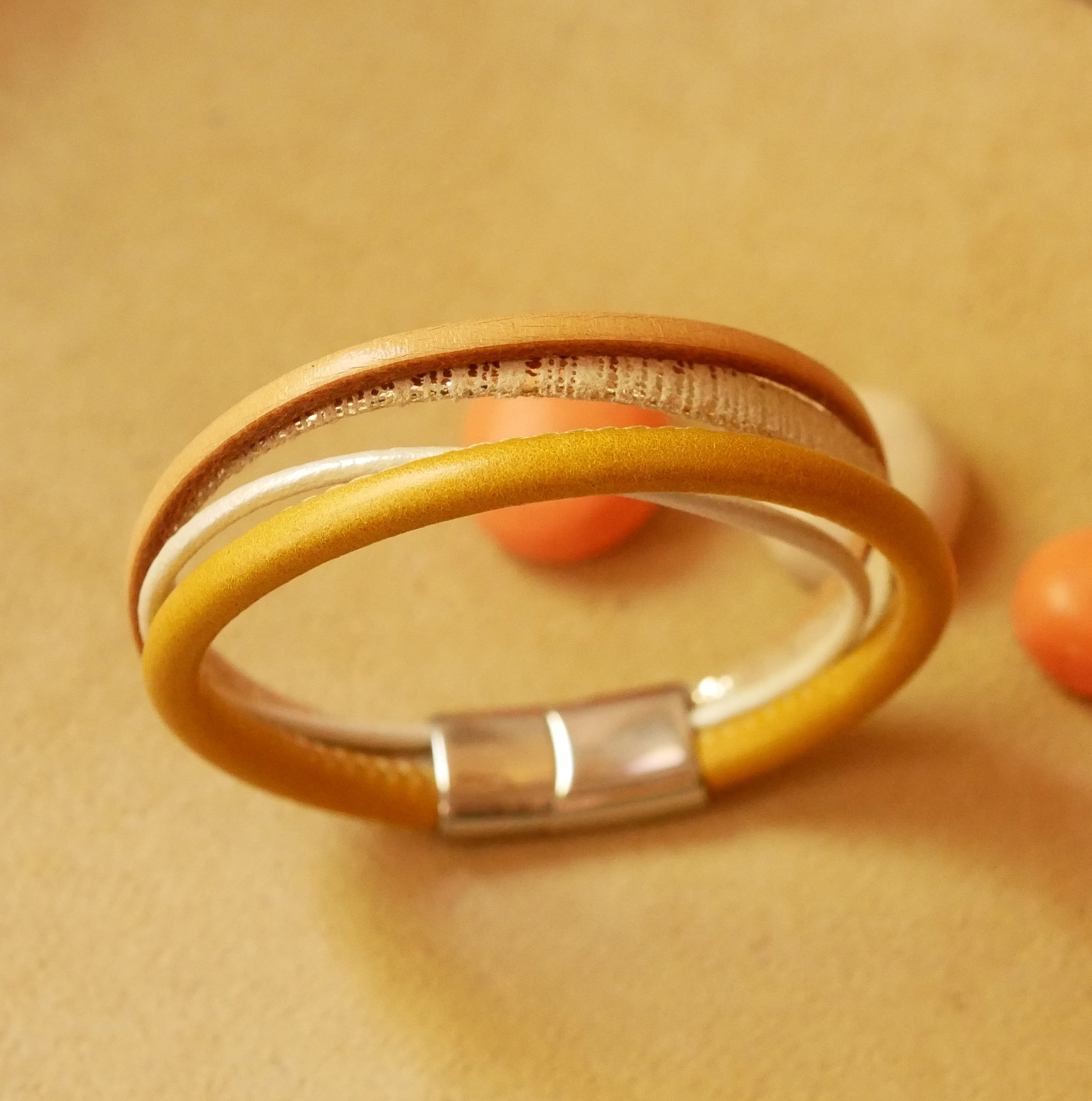 Manschettarmband i beige och guld med flera läderdetaljer