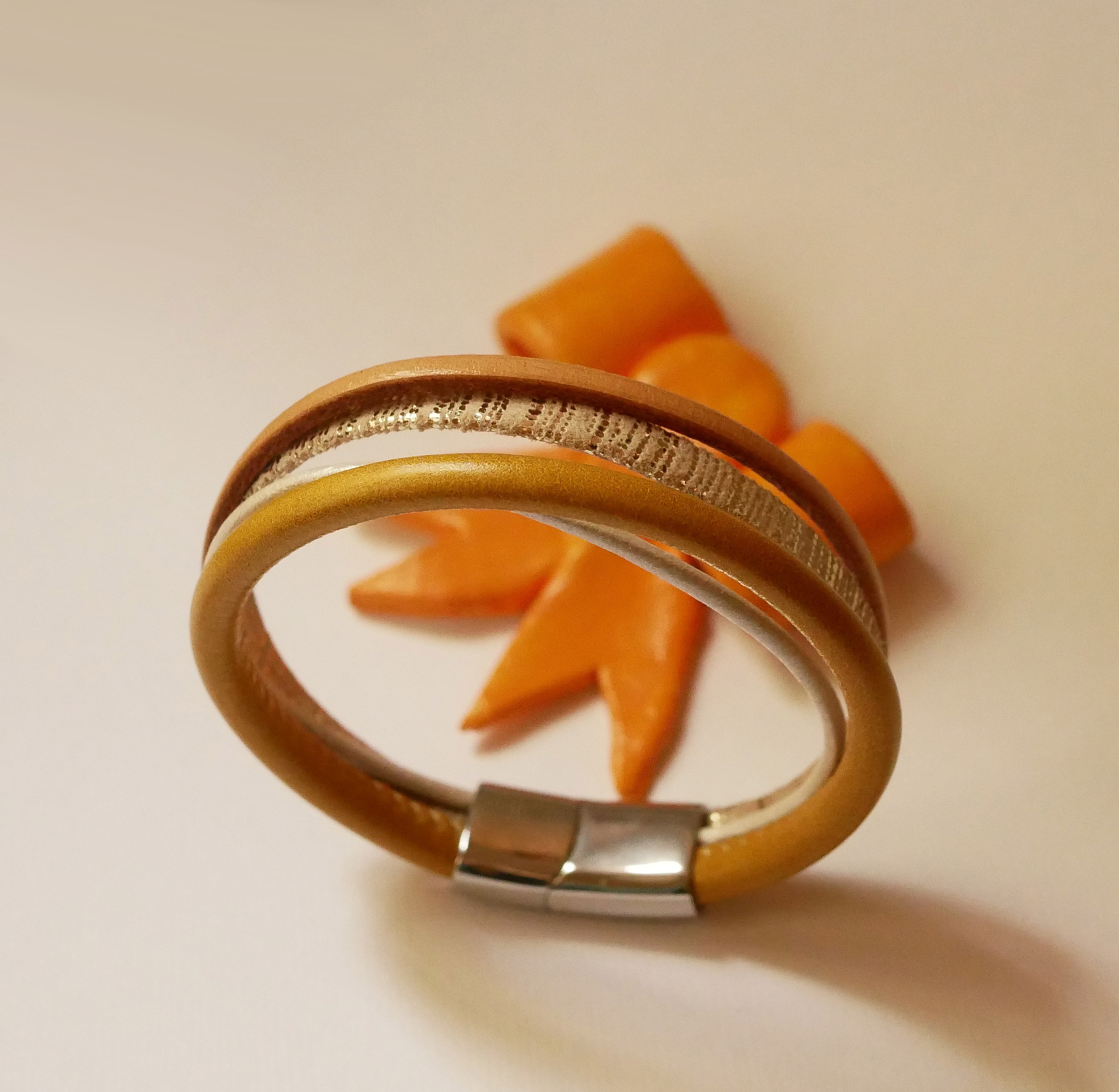 Manschettarmband i beige och guld med flera l&auml;derdetaljer