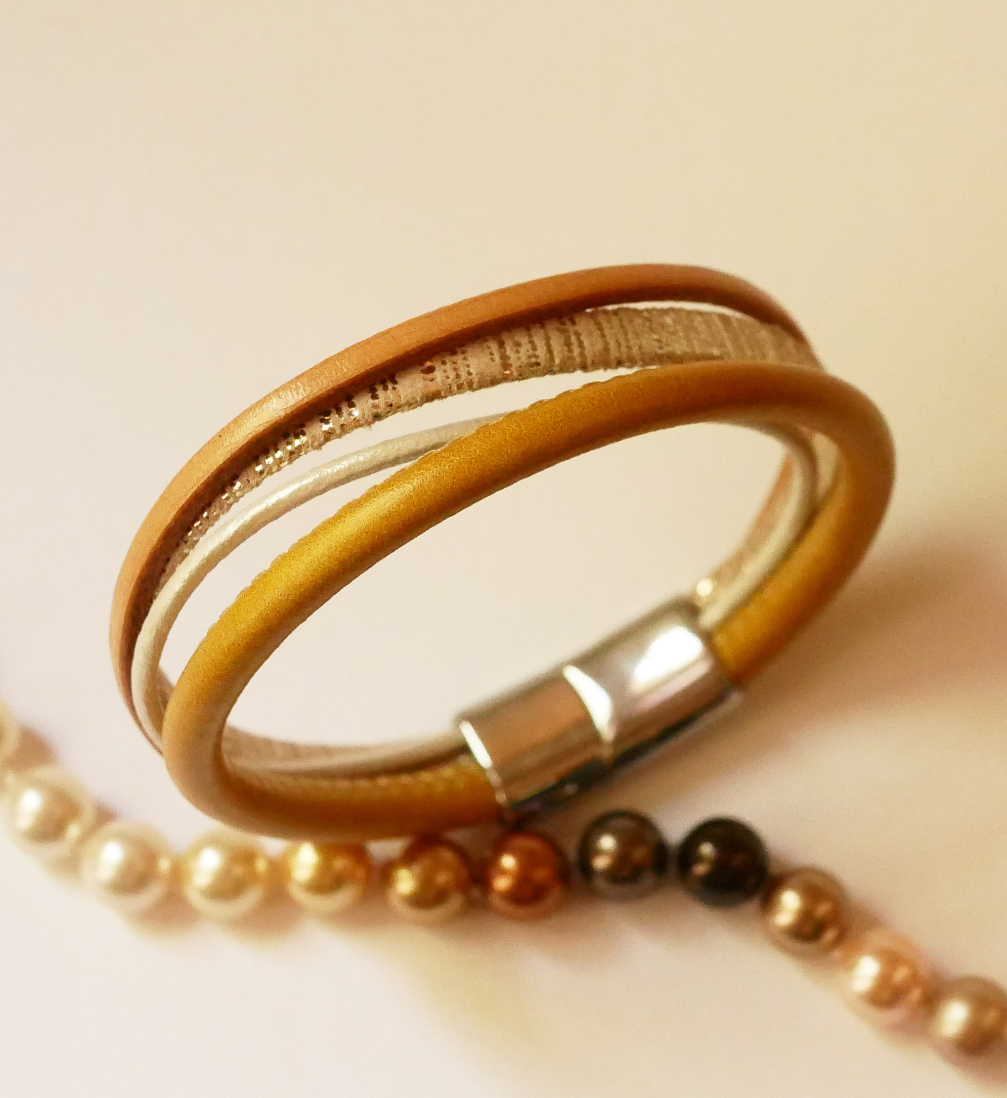 Manschettarmband i beige och guld med flera läderdetaljer