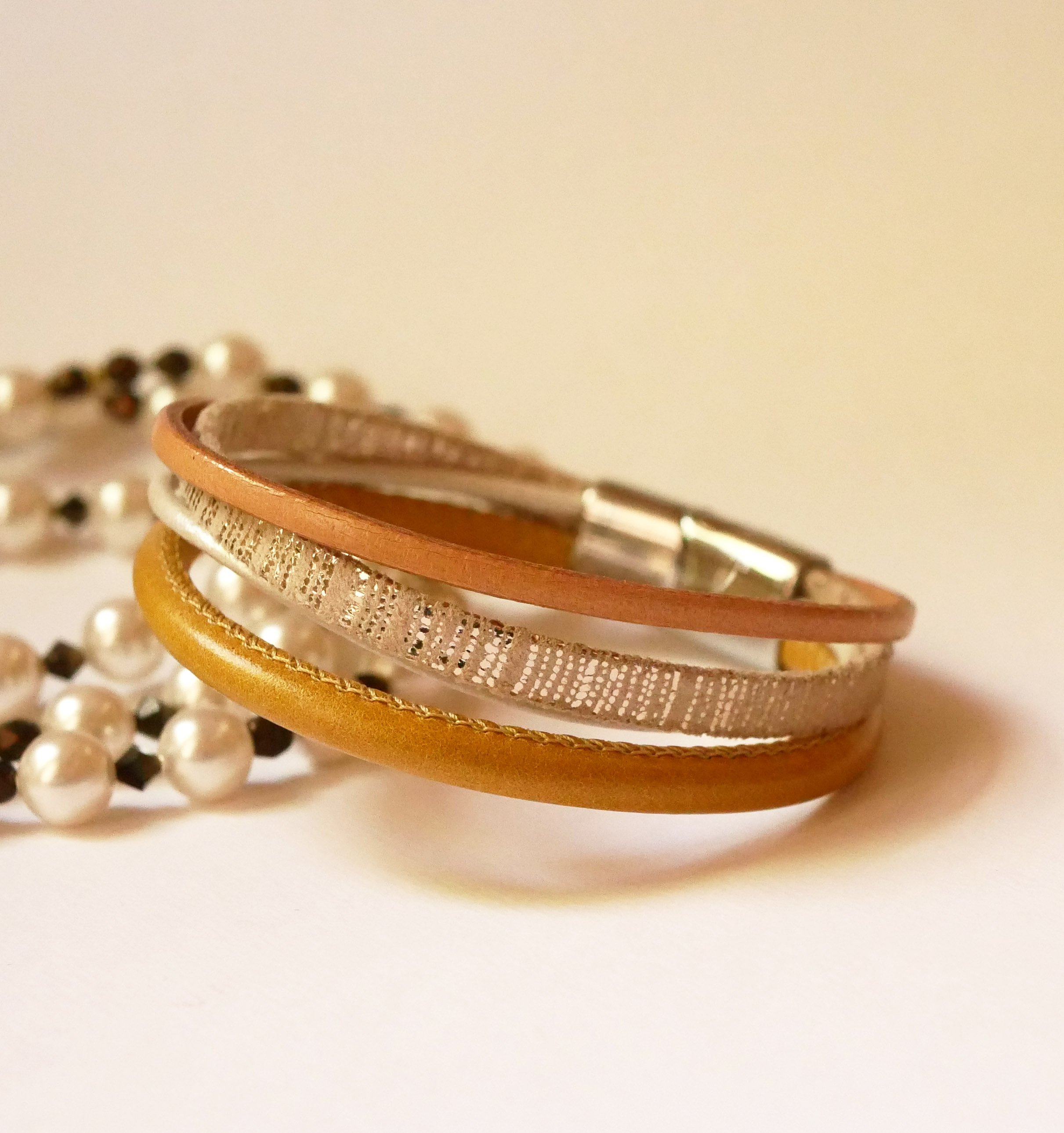 Manschettarmband i beige och guld med flera läderdetaljer