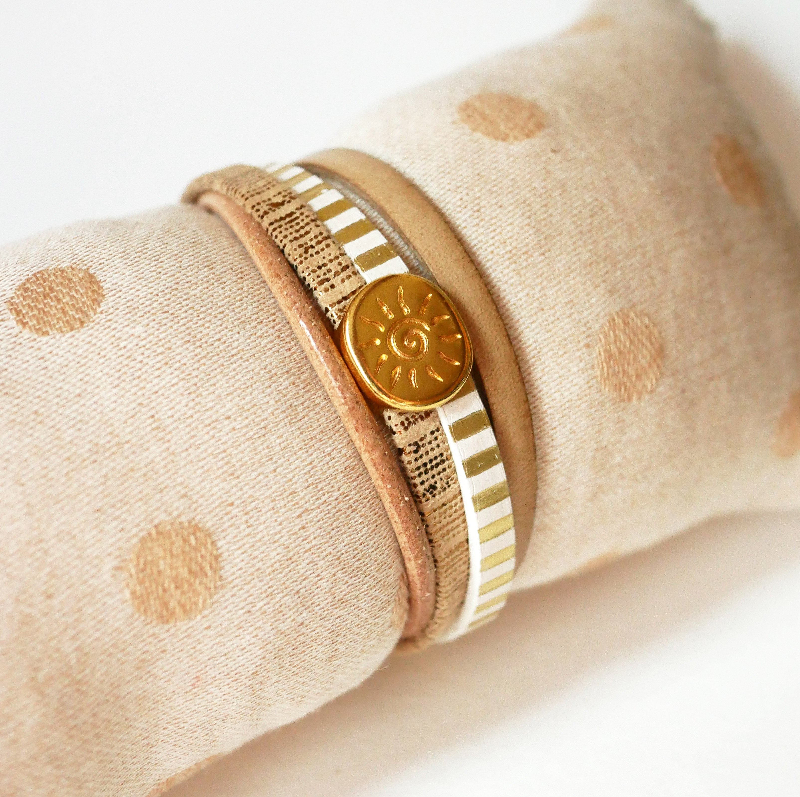 Manschettarmband i läder med flera länkar och solstråleögla i guld