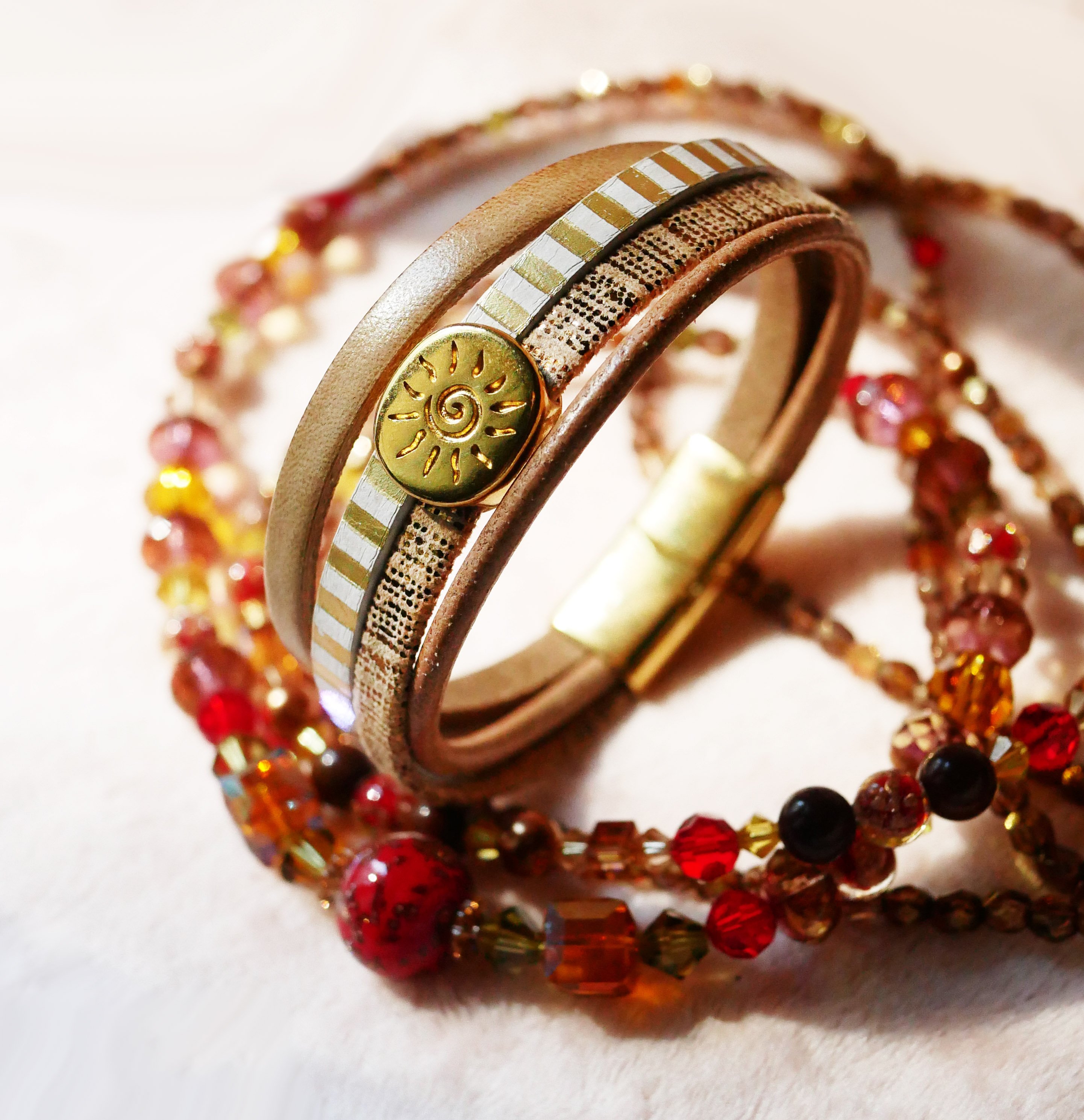 Manschettarmband i läder med flera länkar och solstråleögla i guld