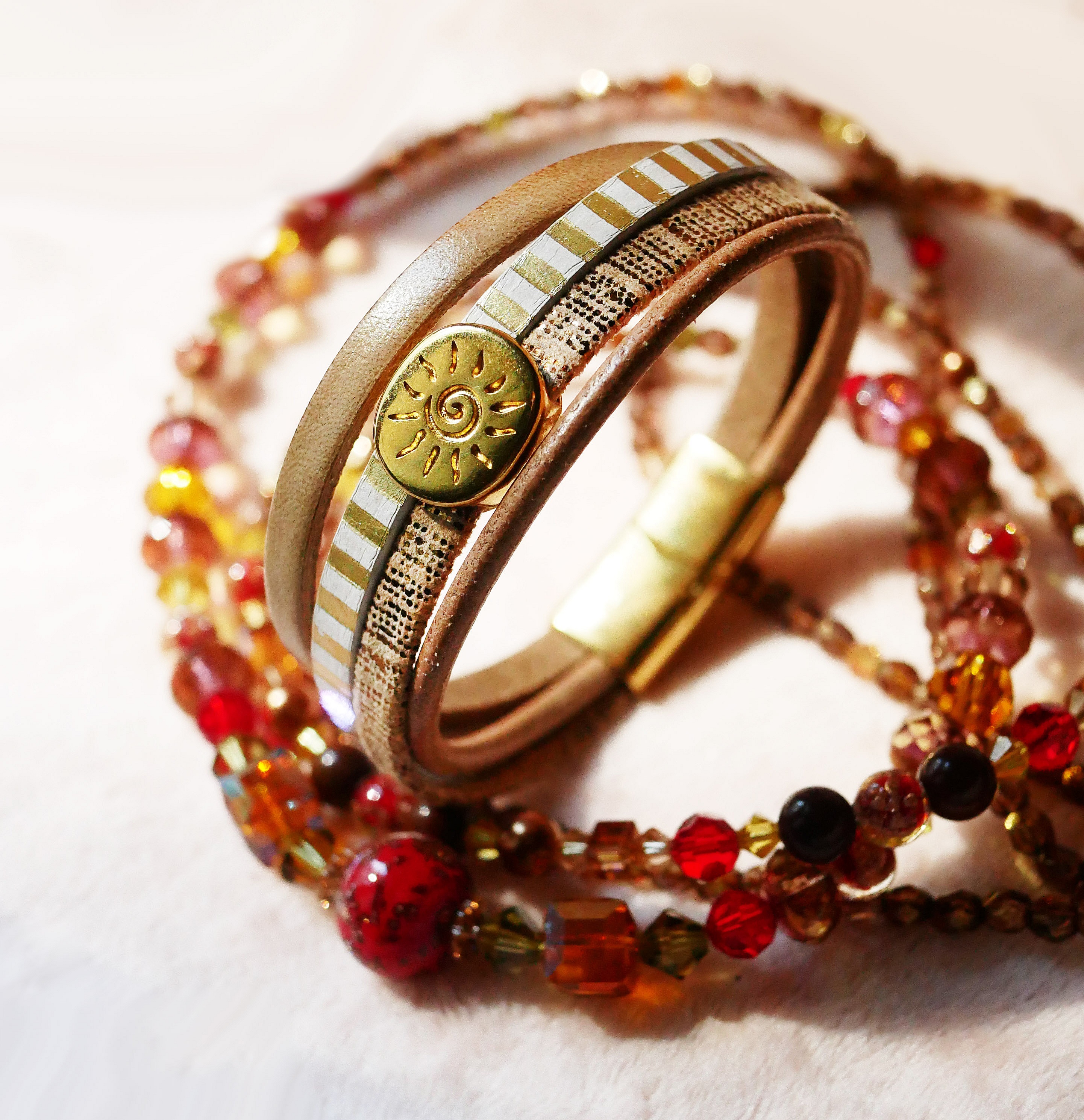 Manschettarmband i l&auml;der med flera l&auml;nkar och solstr&aring;le&ouml;gla i guld