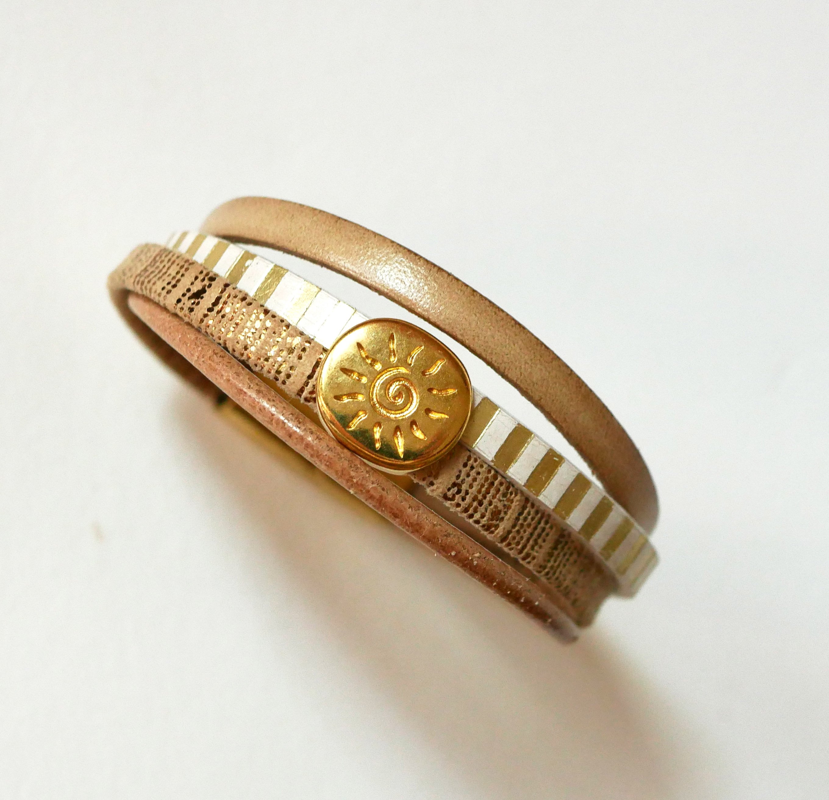 Manschettarmband i läder med flera länkar och solstråleögla i guld