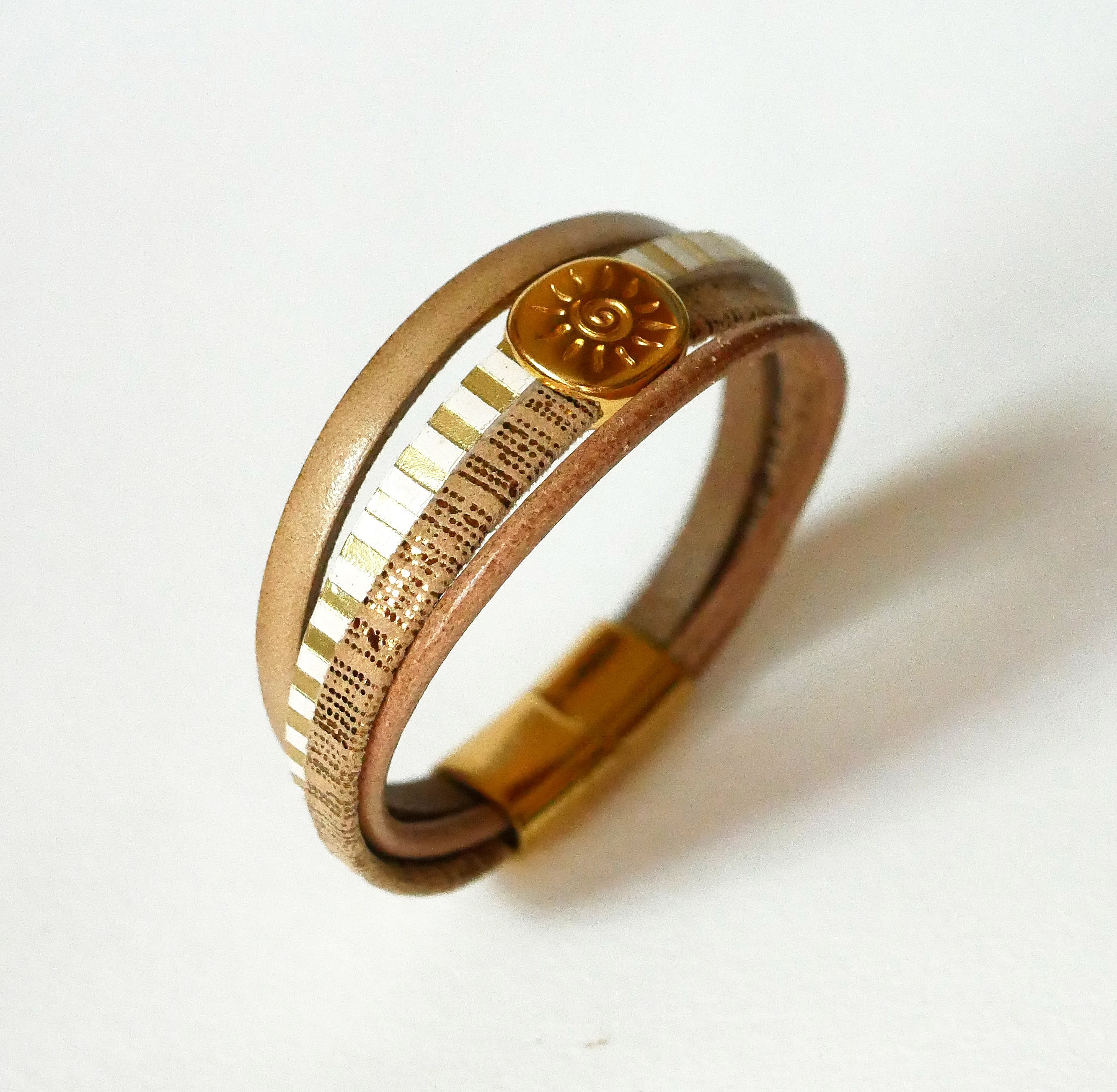 Manschettarmband i l&auml;der med flera l&auml;nkar och solstr&aring;le&ouml;gla i guld