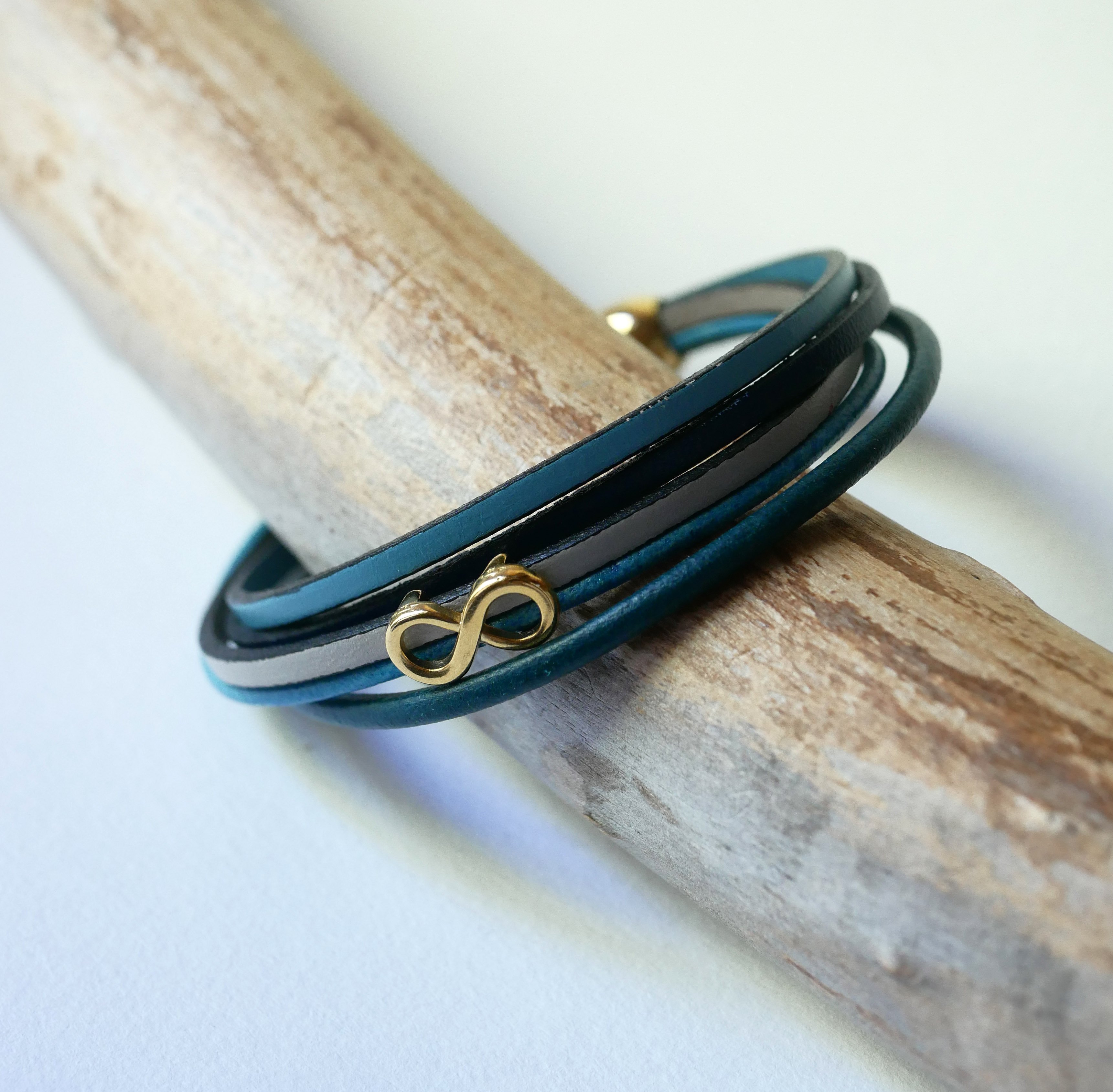 Flerlänkat armband i blåtonat läder med infinitymotiv i guld