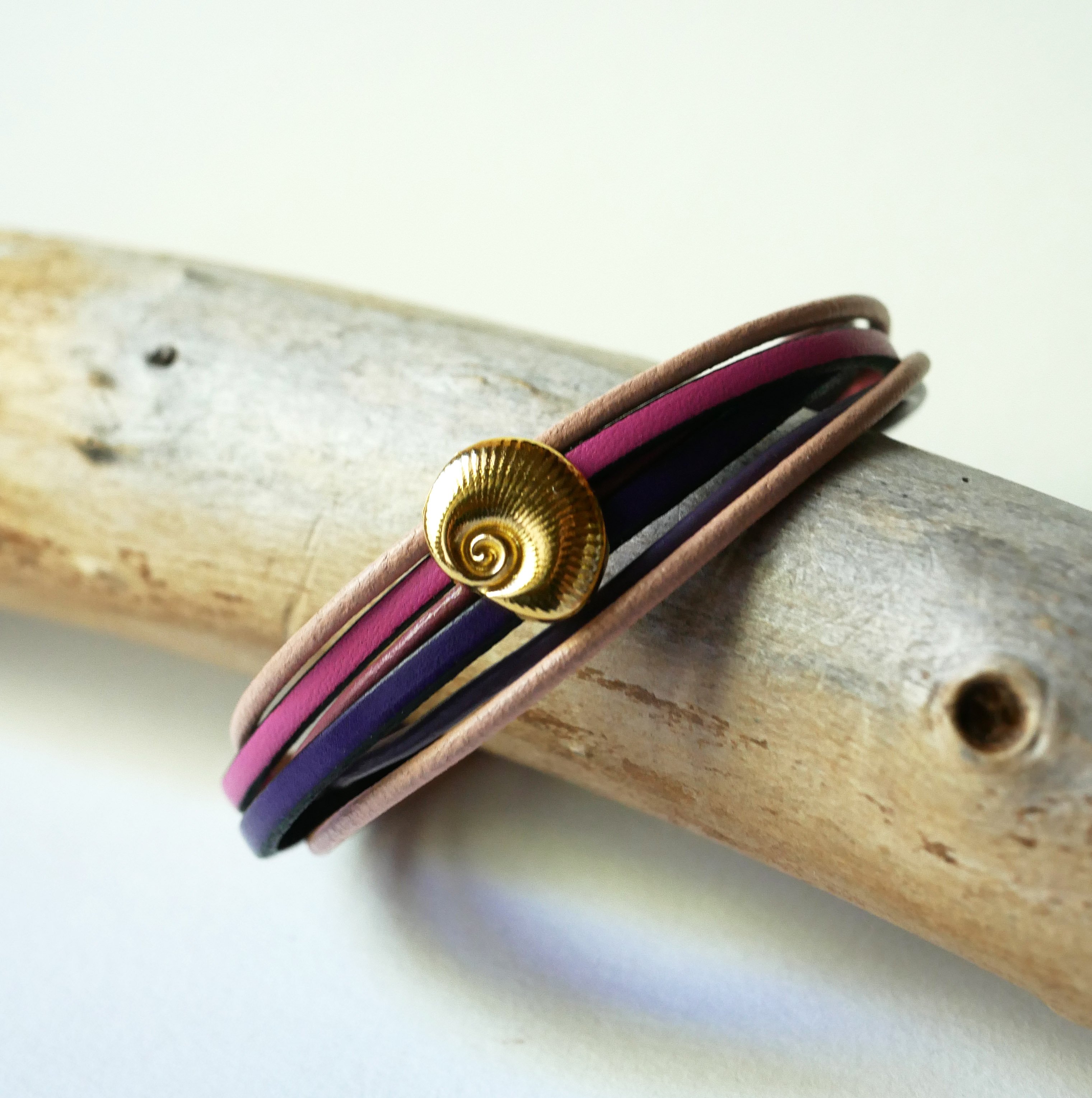 Armband med flera l&auml;nkar i persika- och mauvef&auml;rgat l&auml;der med dekor av guldskal