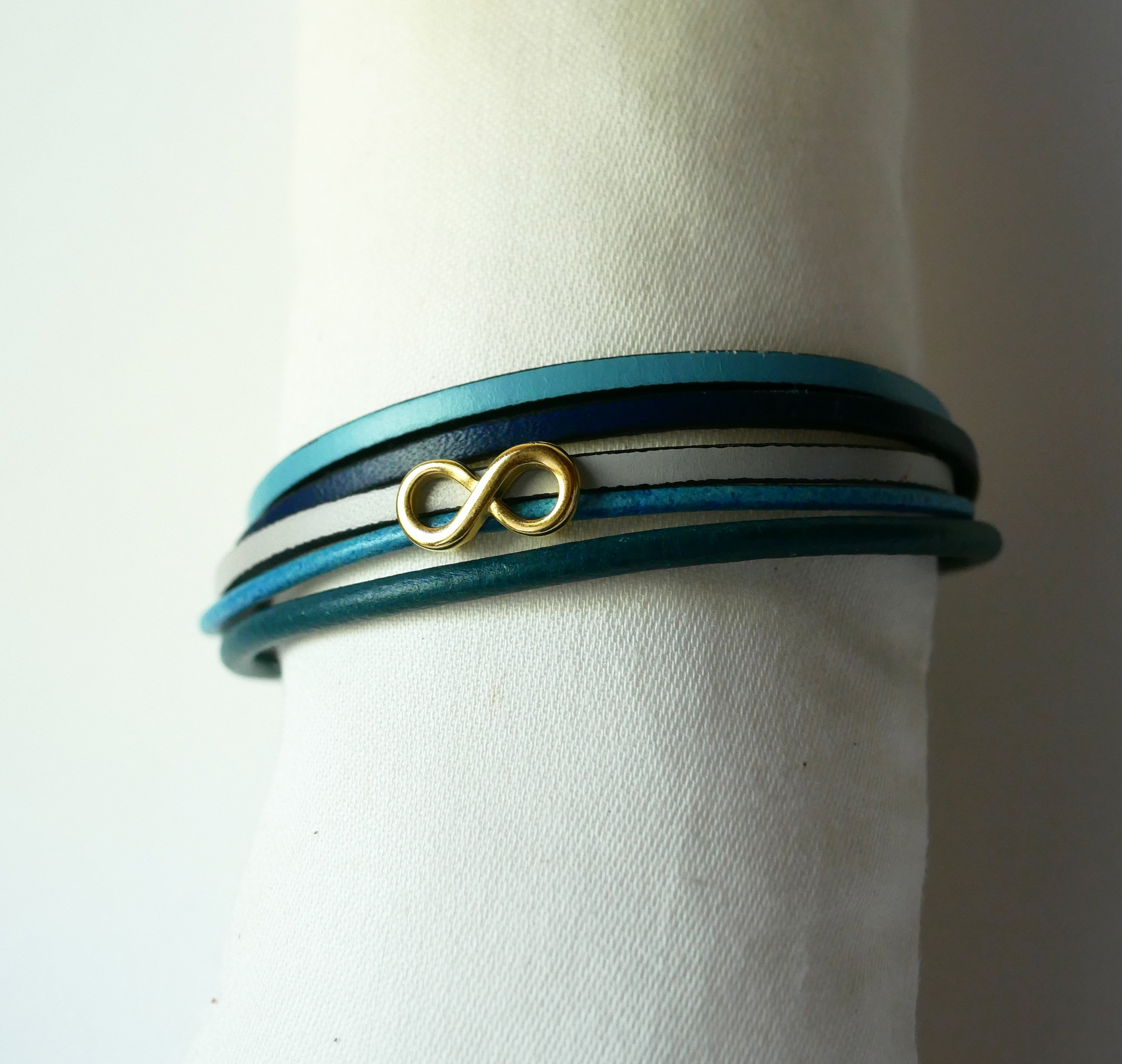 Flerlänkat armband i blåtonat läder med infinitymotiv i guld