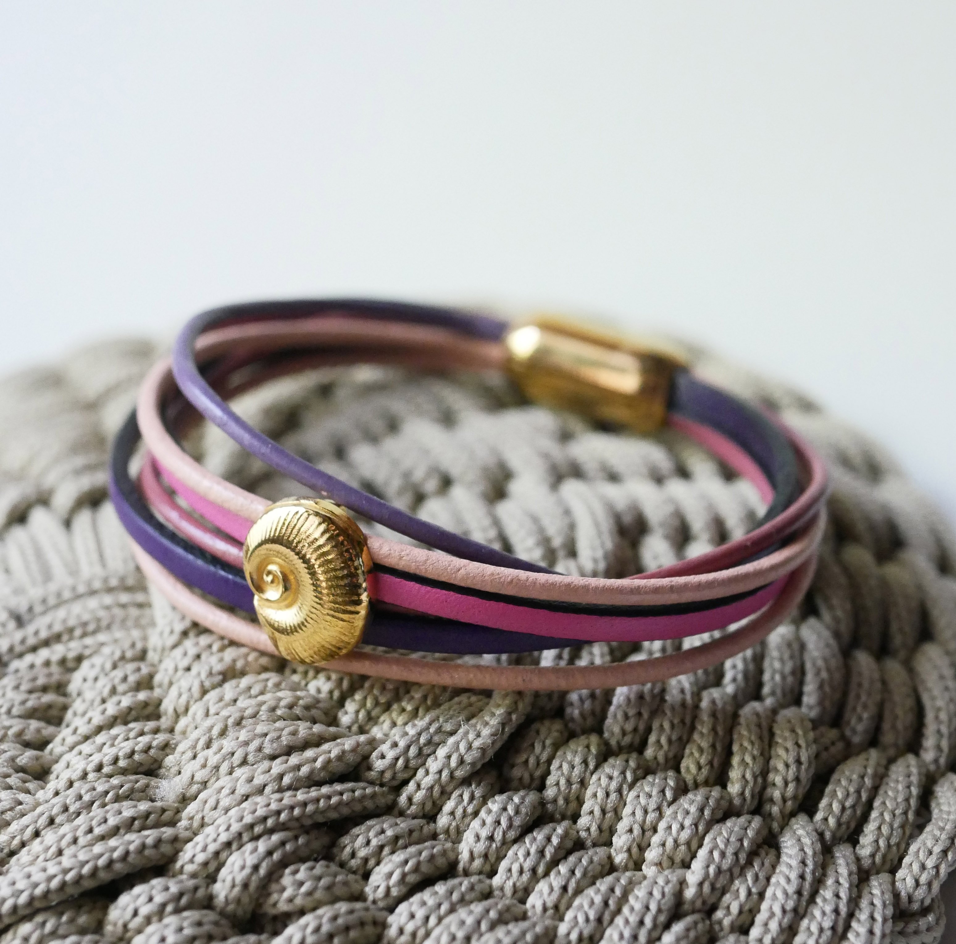 Armband med flera länkar i persika- och mauvefärgat läder med dekor av guldskal
