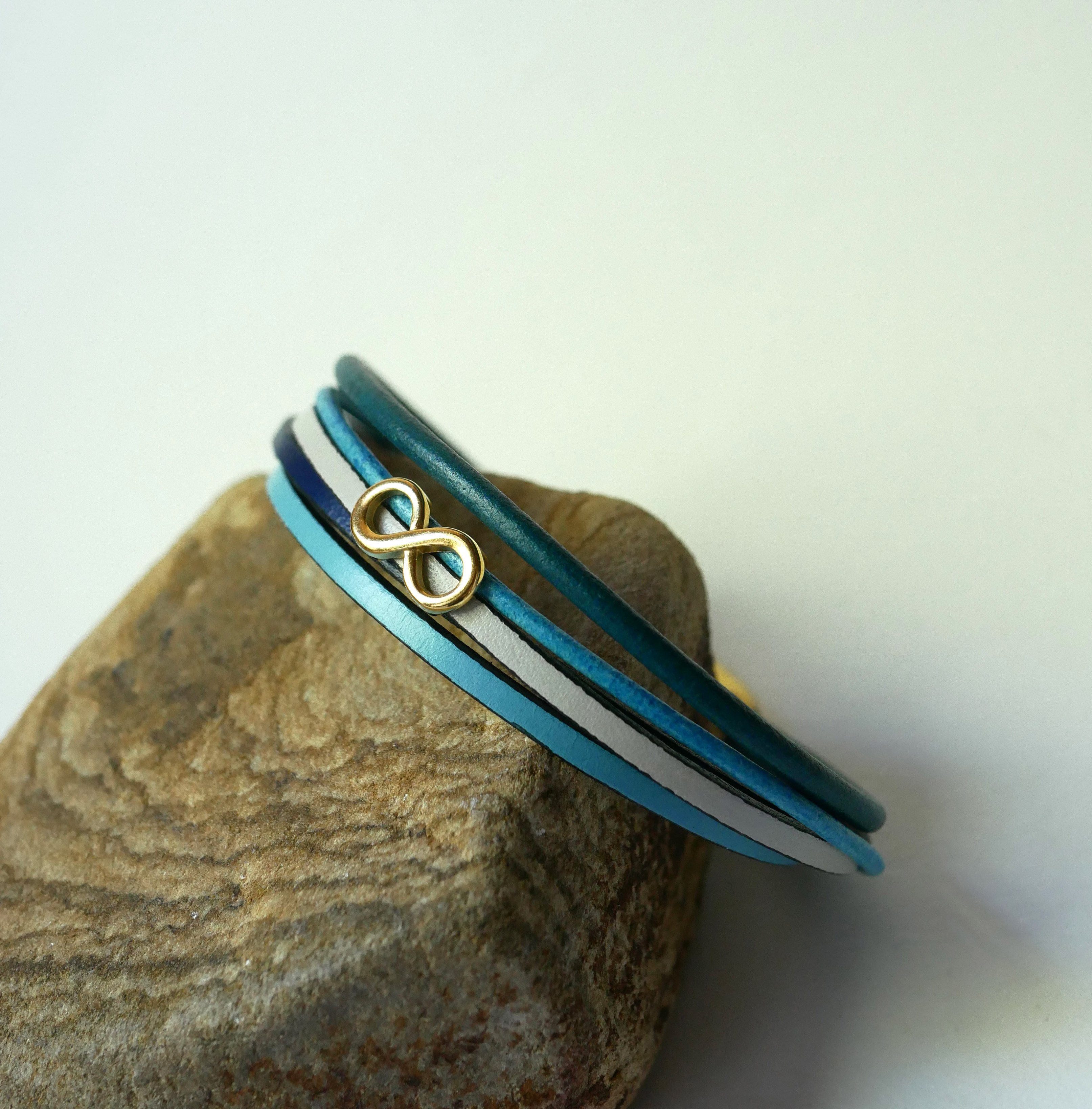 Flerlänkat armband i blåtonat läder med infinitymotiv i guld