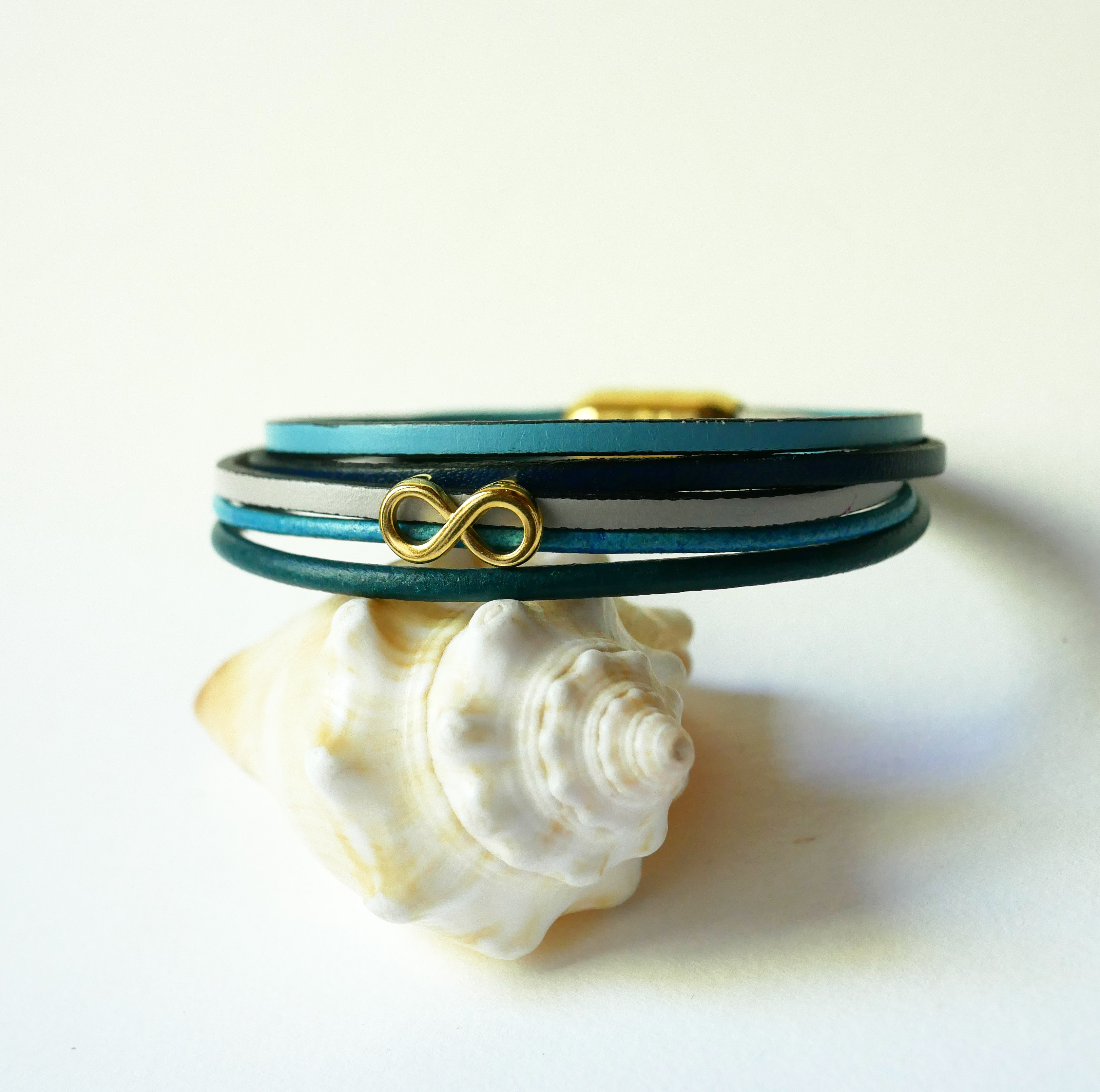 Flerlänkat armband i blåtonat läder med infinitymotiv i guld