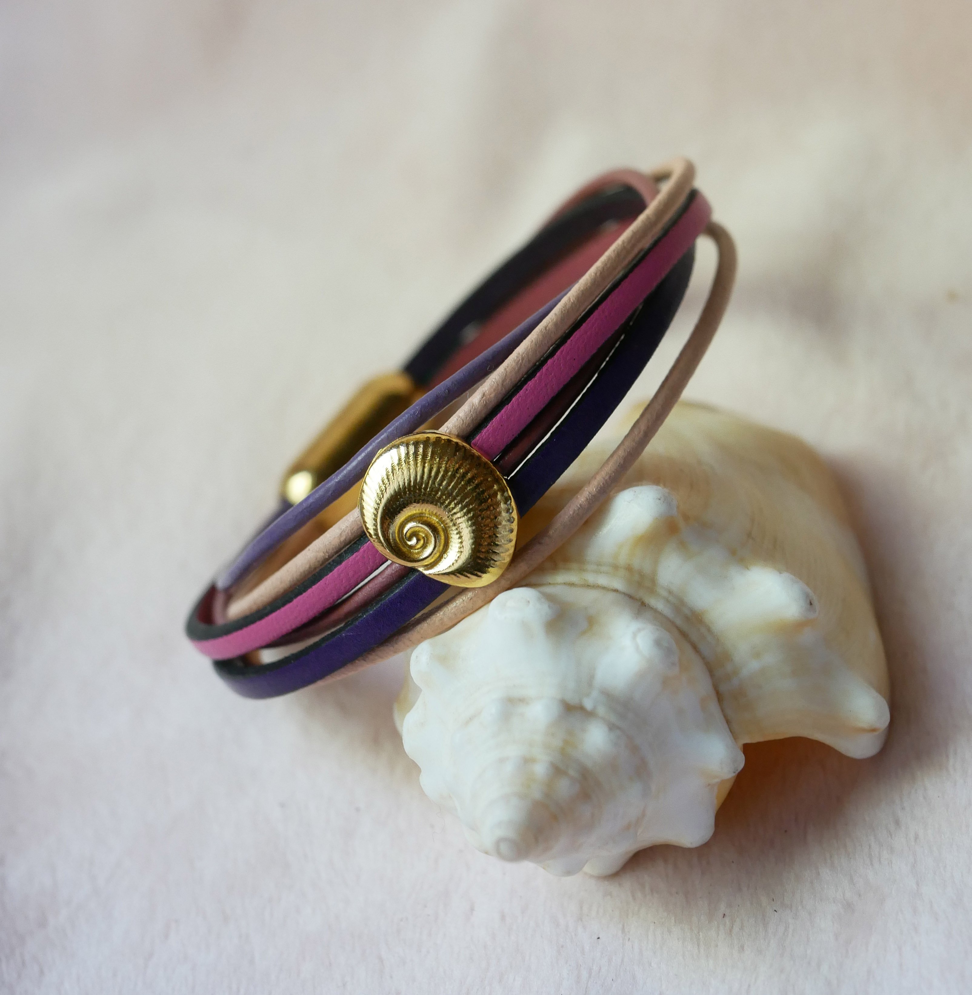 Armband med flera l&auml;nkar i persika- och mauvef&auml;rgat l&auml;der med dekor av guldskal