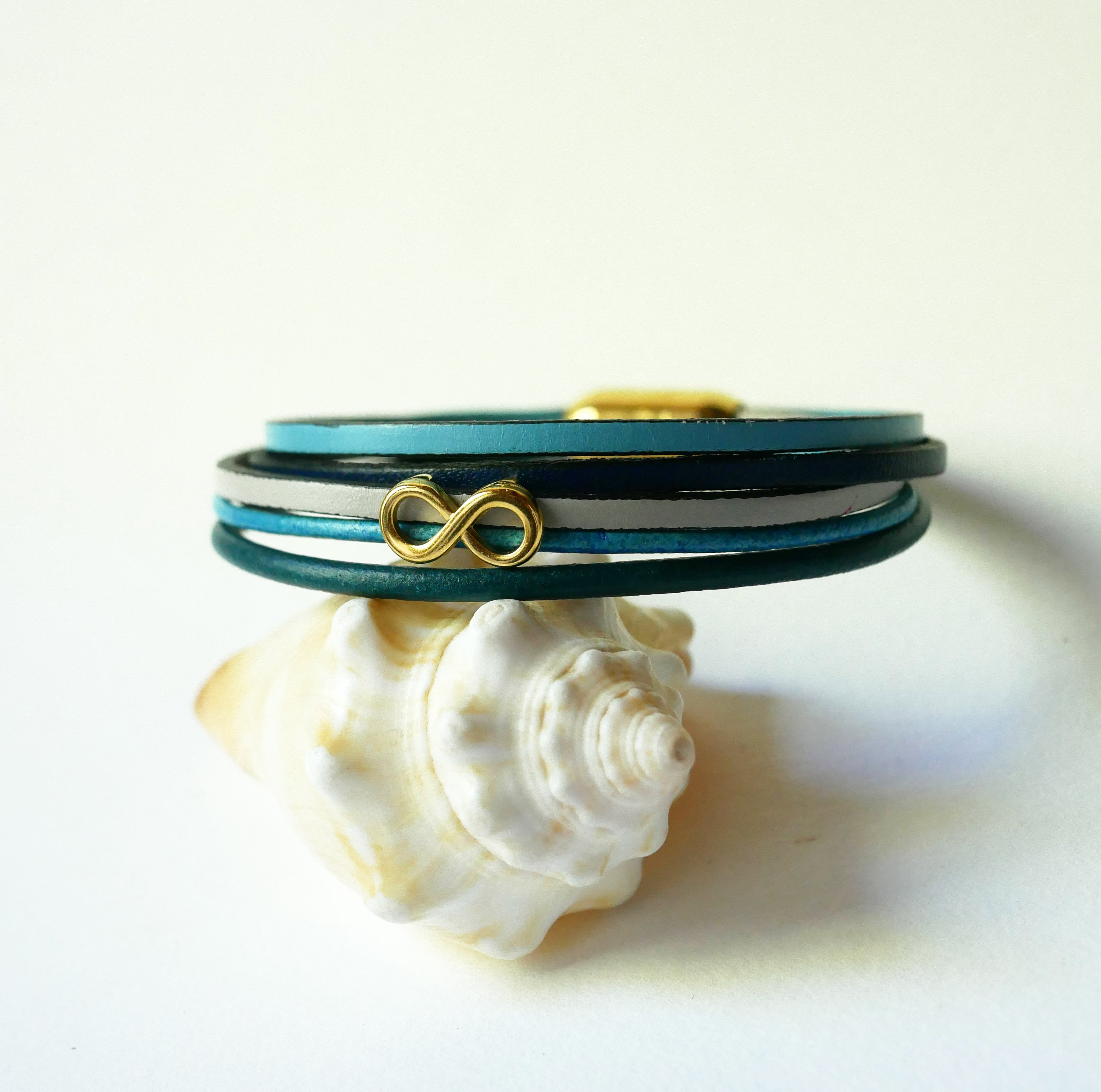 Flerlänkat armband i blåtonat läder med infinitymotiv i guld