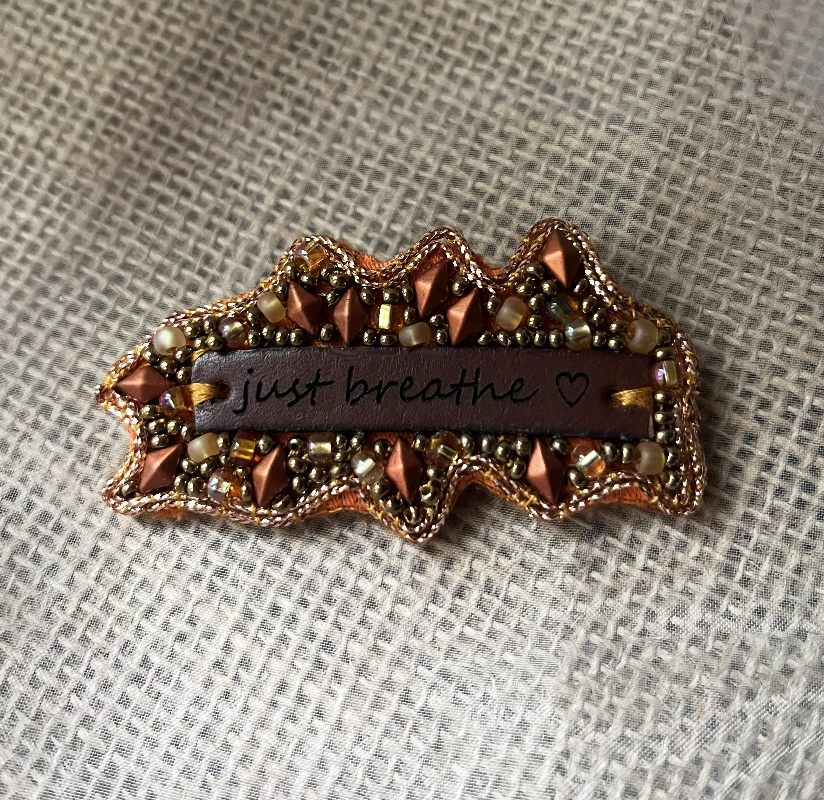 Broche en perles cuivrées à message en cuir gravé "Just breathe"
