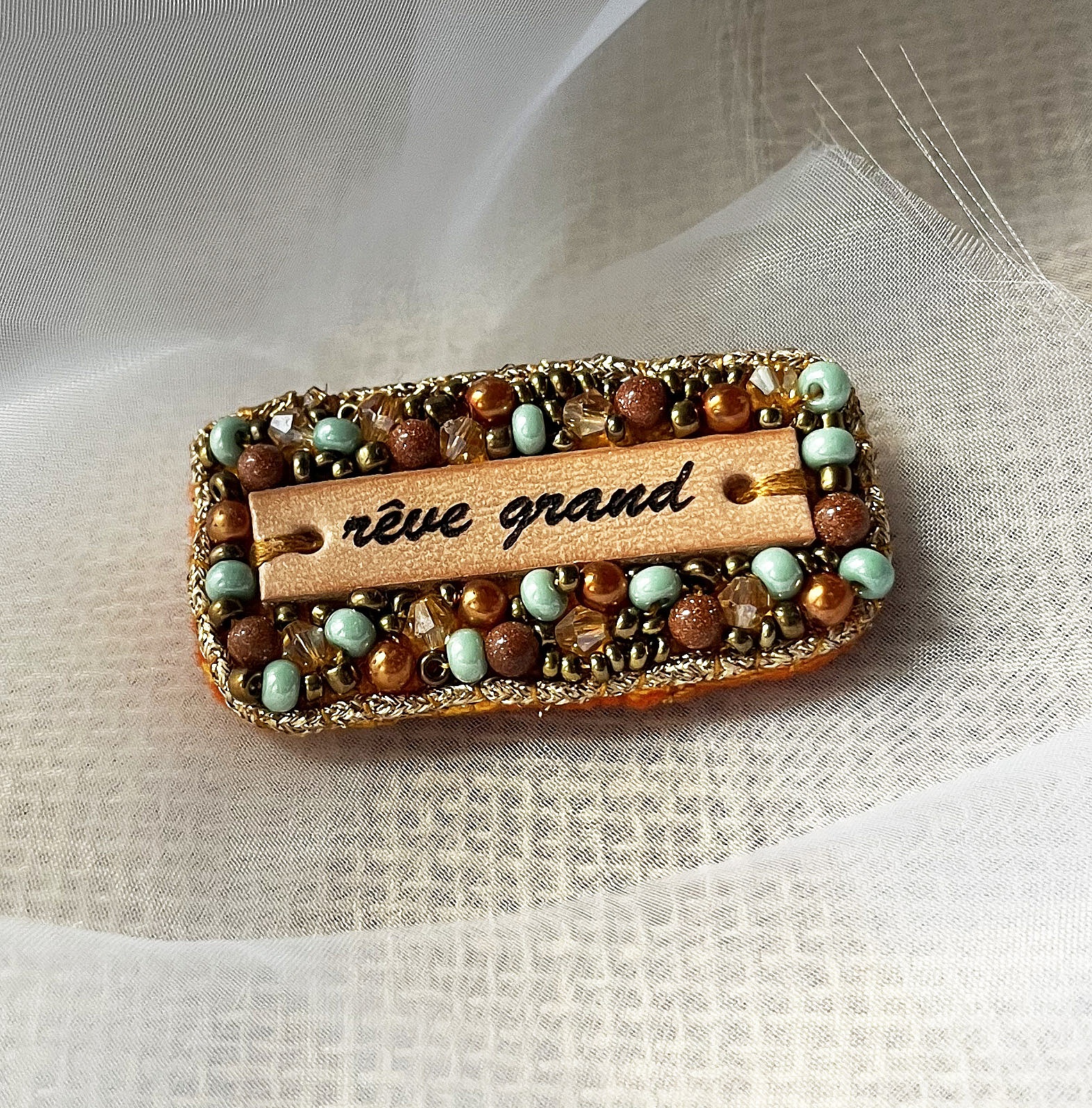 Broche en perles dor&eacute;es &agrave; message en cuir grav&eacute; "r&ecirc;ve grand"