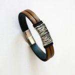 Armband i brunt läder med flätat metallfoder och magnetlås