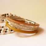 Manschettarmband i beige och guld med flera läderdetaljer