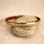 Kvinnoarmband i rosa metalliskt läder med guldpärlor