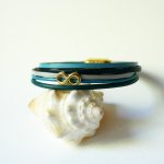 Flerlänkat armband i blåtonat läder med infinitymotiv i guld