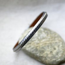 Kvinnoarmband i mörkgrått metalliskt läder med silverfärgade pärlor 