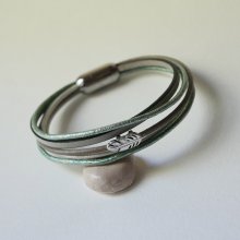 Armband i flera läderfärger i nyanser av beige, ljusgrönt och pärlemor, dekorerat med en liten fjäder